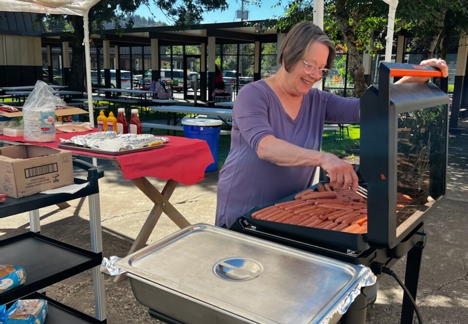 Volunteer Glenda Tate grills hot dogs for incoming Centennial Elementary kindergarteners and their families during Kindergarten Jumpstart in Scio.