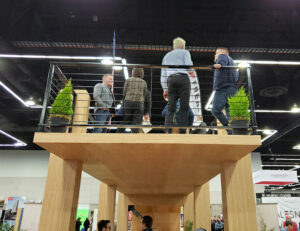 Tyler Freres (far left) and Kyle Freres (far right), network with participants Monday at the annual Mass Timber Conference in Portland. Freres Engineered Wood built the two-story lounge structure for the conference. James Day
