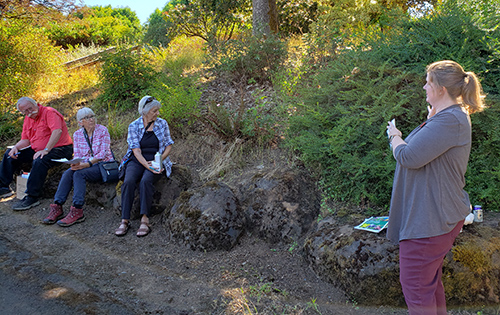 Brooke Edmunds, a horticulturalist with OSU Extension, shows a section of overgrown plants at the Oregon Garden during her discussion of fire-resistant vegetation. James Day