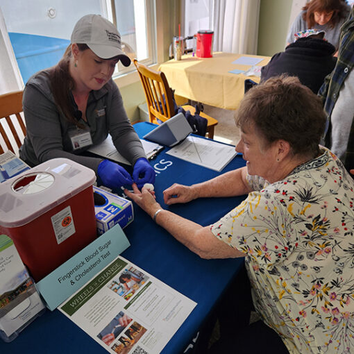 A Santiam Hospital community health worker administers a blood sugar and cholesterol screening test at the April 11 Santiam Canyon Community Health Fair in Mill City. Submitted